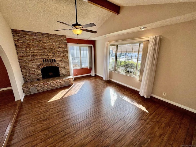 unfurnished living room featuring lofted ceiling with beams, a brick fireplace, dark hardwood / wood-style floors, and a textured ceiling