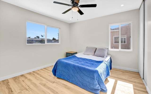 bedroom with multiple windows, ceiling fan, and light hardwood / wood-style floors