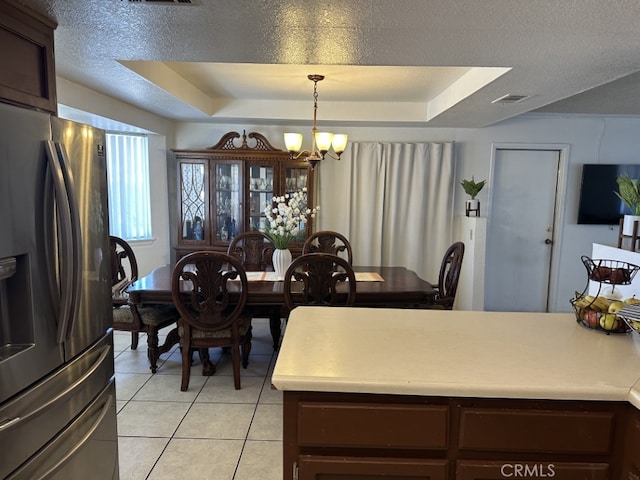 kitchen with light tile patterned floors, stainless steel fridge, a notable chandelier, decorative light fixtures, and a raised ceiling