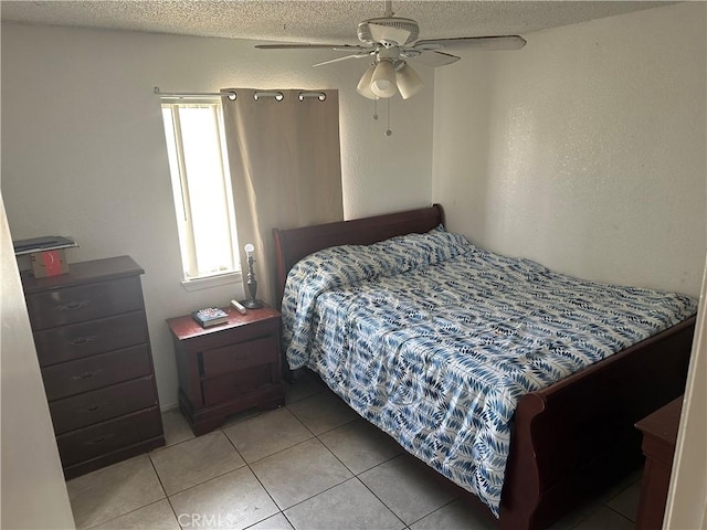 bedroom with ceiling fan, light tile patterned floors, and a textured ceiling