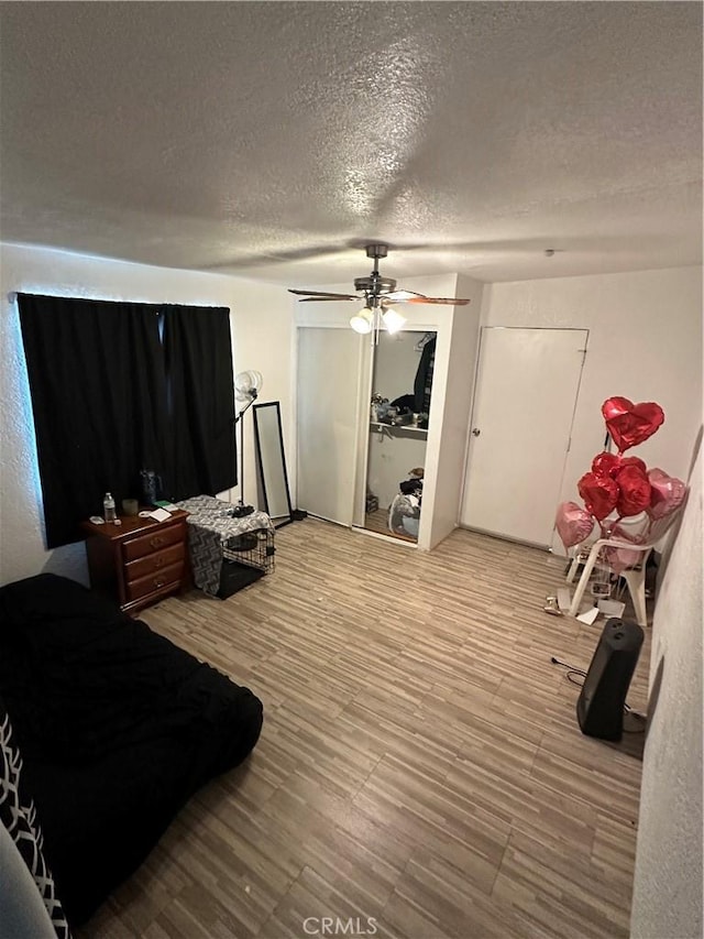 bedroom with ceiling fan, hardwood / wood-style floors, and a textured ceiling