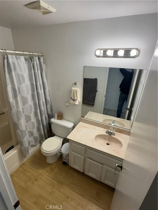 full bathroom with hardwood / wood-style flooring, vanity, toilet, and shower / bath combo with shower curtain