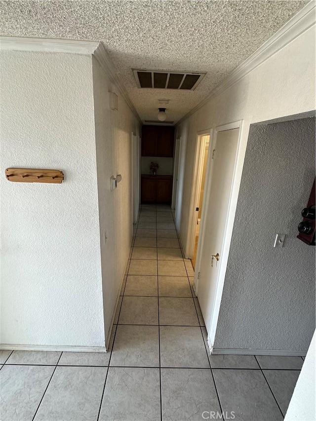 corridor with ornamental molding, light tile patterned floors, and a textured ceiling