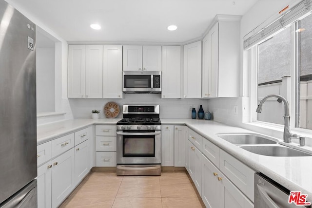 kitchen with stainless steel appliances, sink, white cabinets, and backsplash