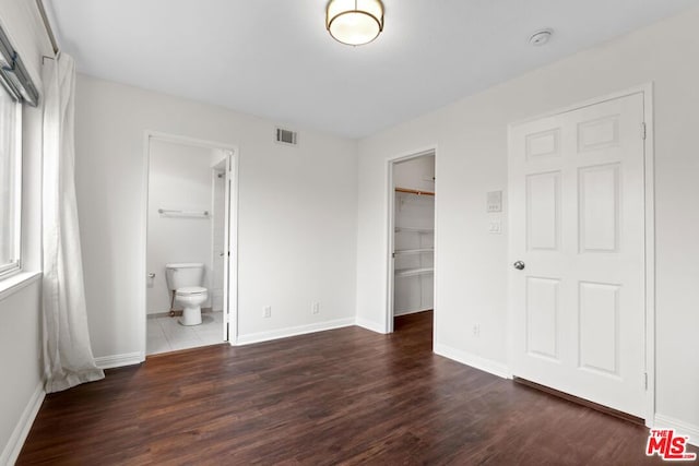 unfurnished bedroom featuring dark hardwood / wood-style flooring, a spacious closet, ensuite bath, and a closet