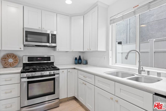 kitchen featuring white cabinetry, stainless steel appliances, sink, and tasteful backsplash