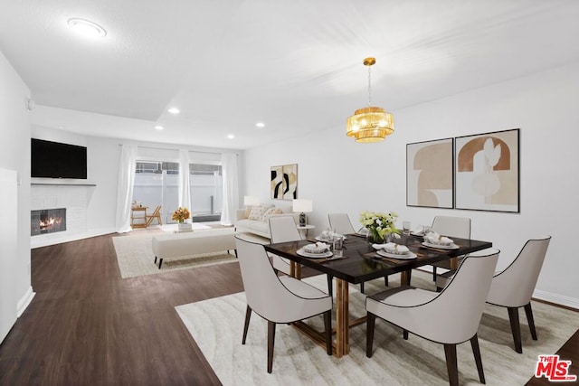 dining space with an inviting chandelier, a fireplace, and hardwood / wood-style floors