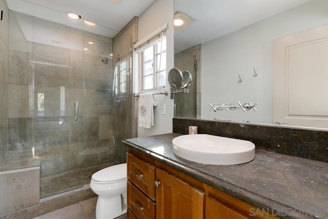 bathroom featuring tile patterned flooring, toilet, vanity, and walk in shower