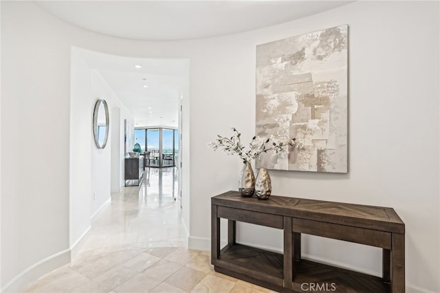 corridor featuring expansive windows and baseboards