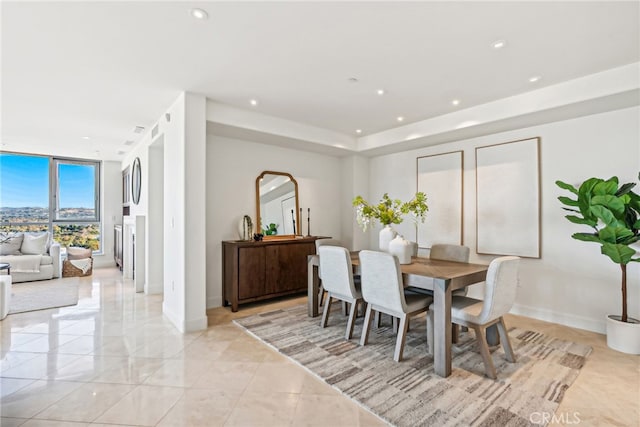 dining area with baseboards, a wall of windows, and recessed lighting