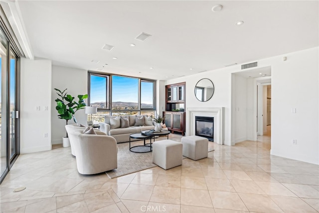 living room featuring a wall of windows, a glass covered fireplace, visible vents, and recessed lighting