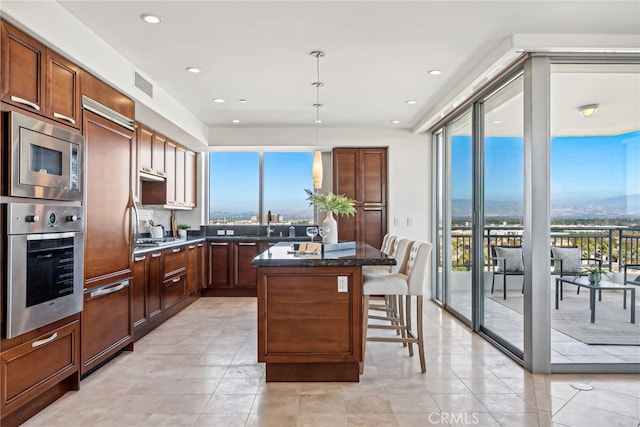 kitchen with visible vents, a kitchen breakfast bar, a center island, hanging light fixtures, and built in appliances