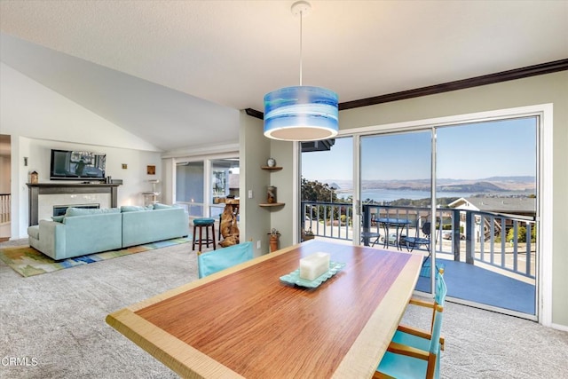 carpeted dining space featuring a water and mountain view, ornamental molding, and vaulted ceiling