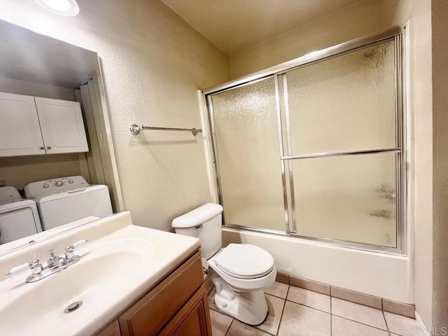 full bathroom featuring bath / shower combo with glass door, vanity, washing machine and clothes dryer, tile patterned floors, and toilet