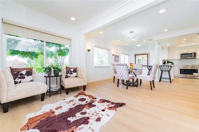 living area with ornamental molding and light hardwood / wood-style floors