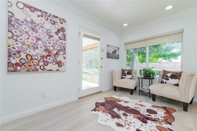 living area with ornamental molding, light hardwood / wood-style floors, and a wealth of natural light