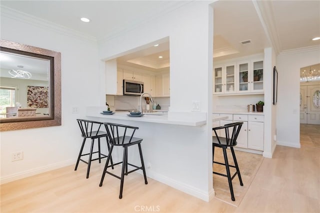 kitchen with white cabinetry, a breakfast bar, sink, and crown molding