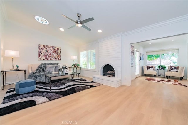 living room featuring crown molding, plenty of natural light, a large fireplace, and wood-type flooring