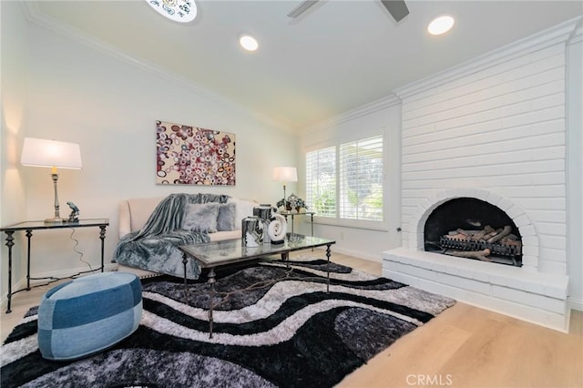 living room featuring crown molding, vaulted ceiling, a large fireplace, and hardwood / wood-style floors