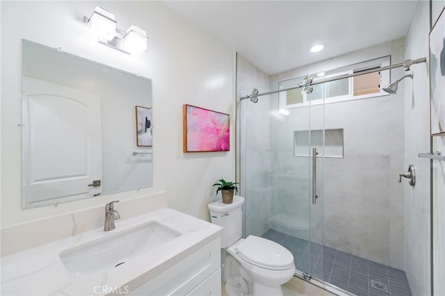 bathroom featuring vanity, toilet, and a shower with door