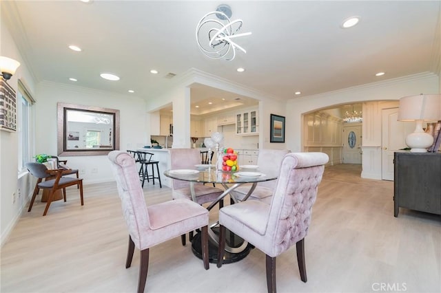 dining room with ornamental molding, light wood-type flooring, and a notable chandelier