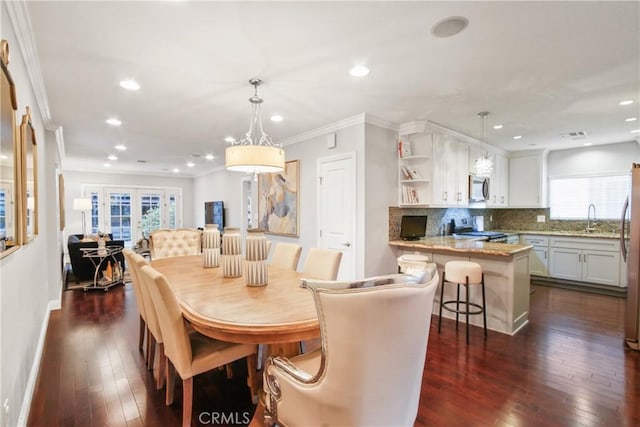 dining space featuring sink, crown molding, dark wood-type flooring, and french doors