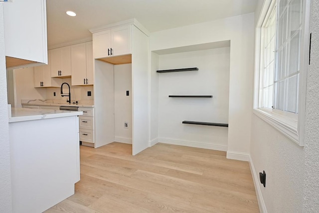 kitchen featuring sink, light hardwood / wood-style floors, and white cabinets