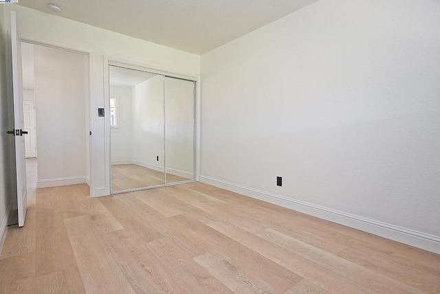 unfurnished bedroom featuring light wood-type flooring and a closet