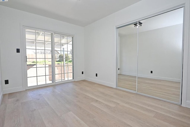 unfurnished bedroom featuring access to outside, light hardwood / wood-style floors, and a closet