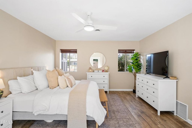 bedroom featuring multiple windows, dark wood-type flooring, and ceiling fan