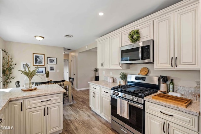 kitchen featuring stainless steel appliances, light stone countertops, and light hardwood / wood-style flooring