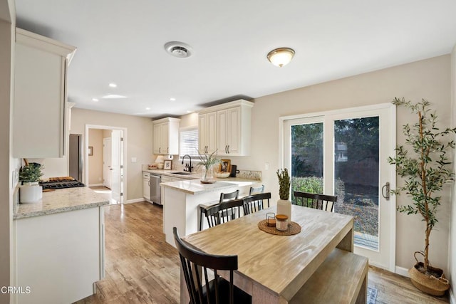 dining area featuring sink, light hardwood / wood-style flooring, and a healthy amount of sunlight