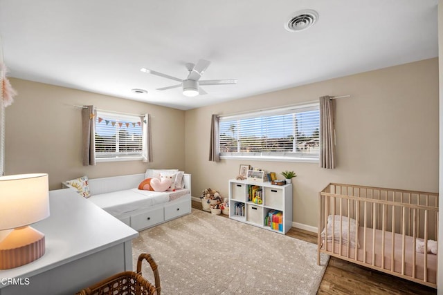 bedroom with multiple windows, hardwood / wood-style floors, and ceiling fan