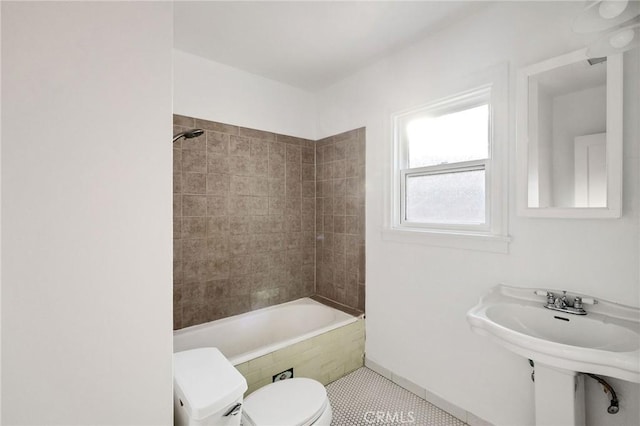 bathroom featuring tiled shower / bath, tile patterned floors, and toilet