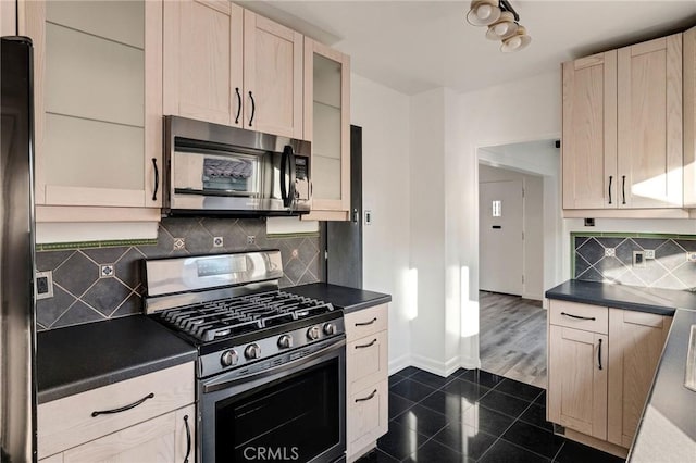 kitchen featuring backsplash, light brown cabinets, dark tile patterned flooring, and appliances with stainless steel finishes