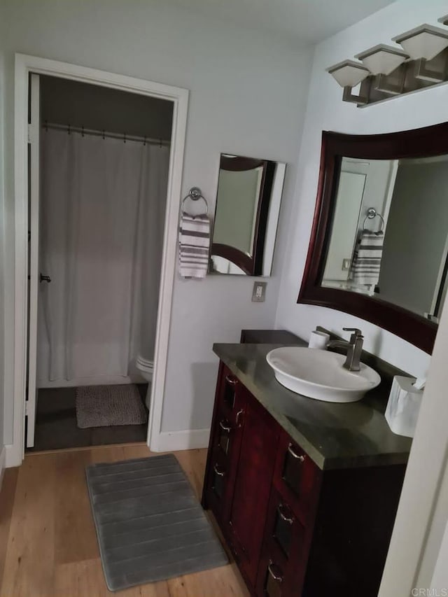 bathroom with vanity, wood-type flooring, curtained shower, and toilet