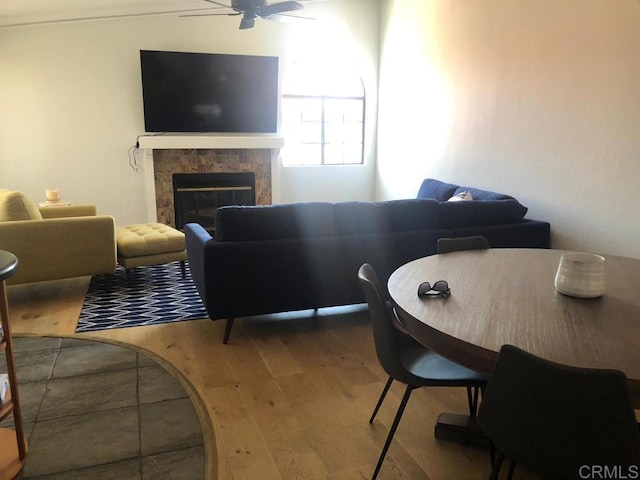 living room featuring ceiling fan, wood-type flooring, and a tile fireplace