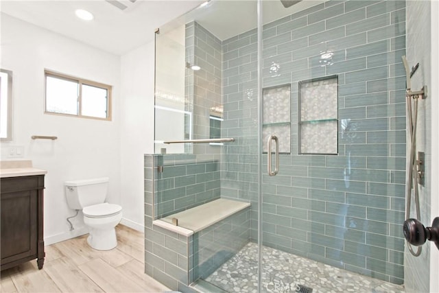 bathroom with vanity, toilet, a shower with door, and hardwood / wood-style floors