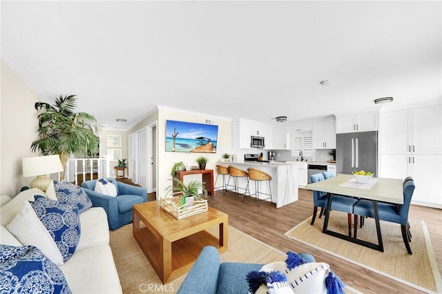 living room featuring sink, light hardwood / wood-style flooring, and ornamental molding