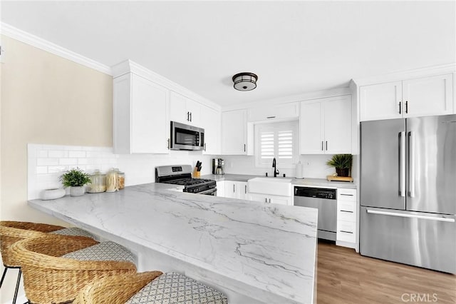 kitchen with sink, ornamental molding, white cabinets, and appliances with stainless steel finishes