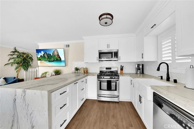 kitchen featuring sink, white cabinets, light stone counters, kitchen peninsula, and stainless steel appliances