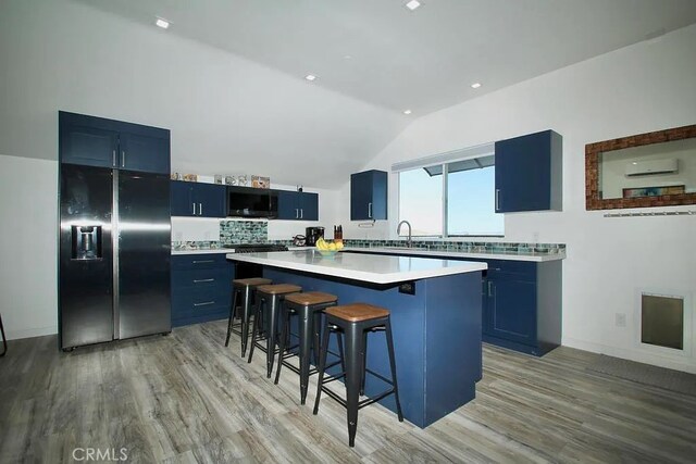 kitchen featuring a kitchen bar, a center island, black refrigerator with ice dispenser, and blue cabinets