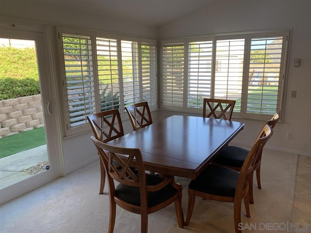 carpeted dining area featuring plenty of natural light and vaulted ceiling