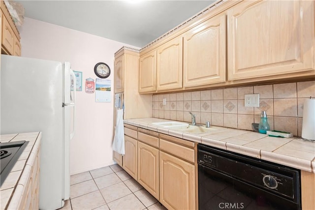 kitchen featuring sink, tile countertops, light tile patterned floors, decorative backsplash, and black appliances