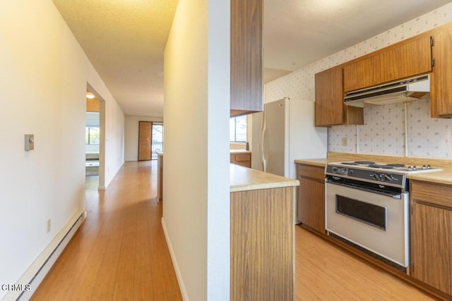 kitchen featuring a wealth of natural light, light hardwood / wood-style floors, gas range gas stove, and baseboard heating