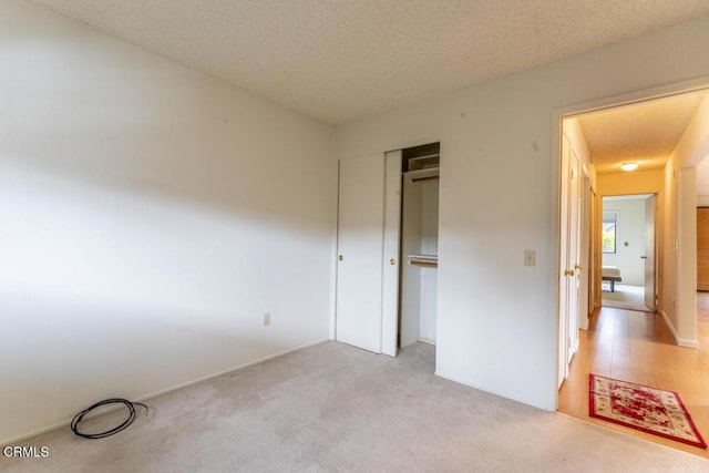 unfurnished bedroom with a closet, light carpet, and a textured ceiling