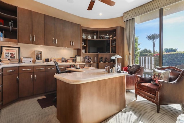 kitchen featuring ceiling fan, a kitchen bar, and dark brown cabinetry