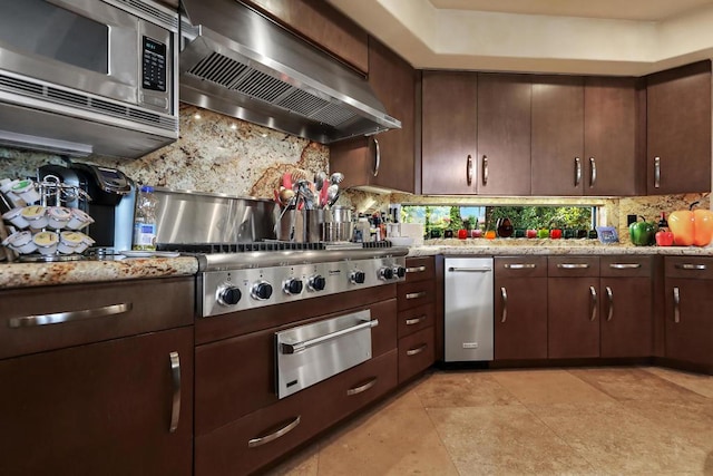 kitchen featuring appliances with stainless steel finishes, backsplash, dark brown cabinetry, and wall chimney exhaust hood