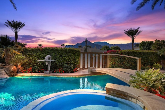 pool at dusk with an in ground hot tub and a mountain view