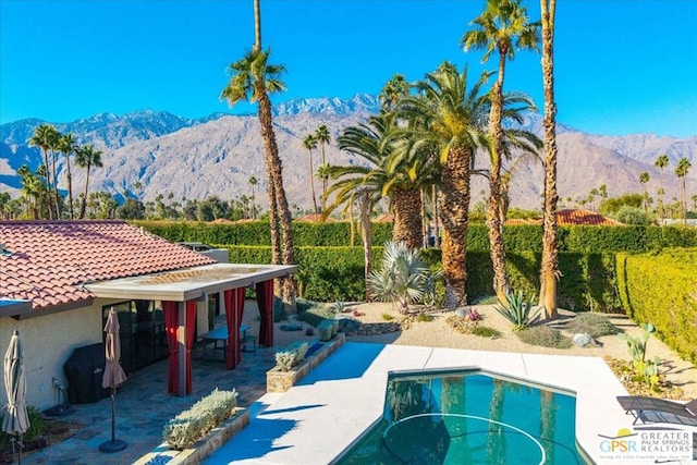 view of swimming pool with a mountain view and a patio area